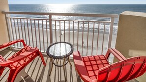 A balcony with a view of the ocean, featuring red chairs and a small table. - Tropical oceanfront resort with shops, restaurants, pools, lazy river-paradise! Sleeps 4. (North Myrtle Beach)
