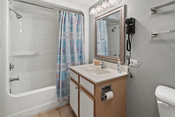 A bathroom with a bathtub, a sink with a mirror, a toilet, and a shower curtain. - Tropical oceanfront resort with shops, restaurants, pools, lazy river-paradise! Sleeps 4. (North Myrtle Beach)