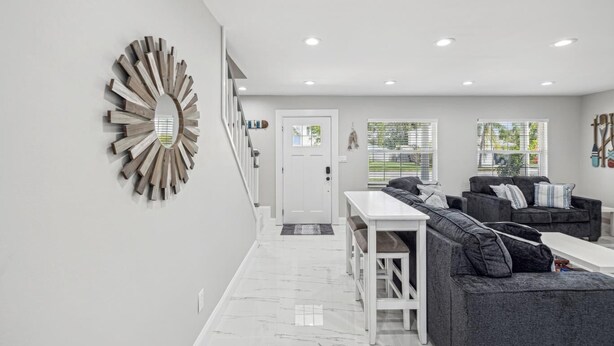A modern living room with a grey sofa, a white coffee table, and a unique wooden wall art piece. - Newly Renovated Luxury Home with an In-ground Pool in Tampa Bay! (Tampa)