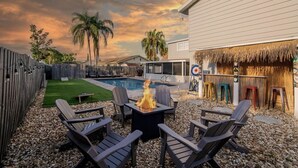 A backyard with a fire pit, outdoor seating, a pool, and a thatched structure. - Newly Renovated Luxury Home with an In-ground Pool in Tampa Bay! (Tampa)