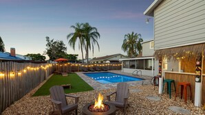 A backyard with a swimming pool, a fire pit, and outdoor seating. - Newly Renovated Luxury Home with an In-ground Pool in Tampa Bay! (Tampa)