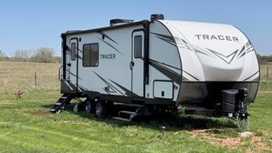 A white RV with the brand name 'TRACER' on its side, parked on a grassy field. - Fully Equipped Camper-Quiet Campground near Medora (Belfield)