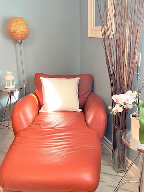 A red leather sofa with a white pillow against a light blue wall, a floor lamp, and a vase with white orchids. - B23~Sunny Terrace+17 Bed/Sofa bed+6 Room+6 Full Bath+Free parking~100 WalkScore (Montréal)