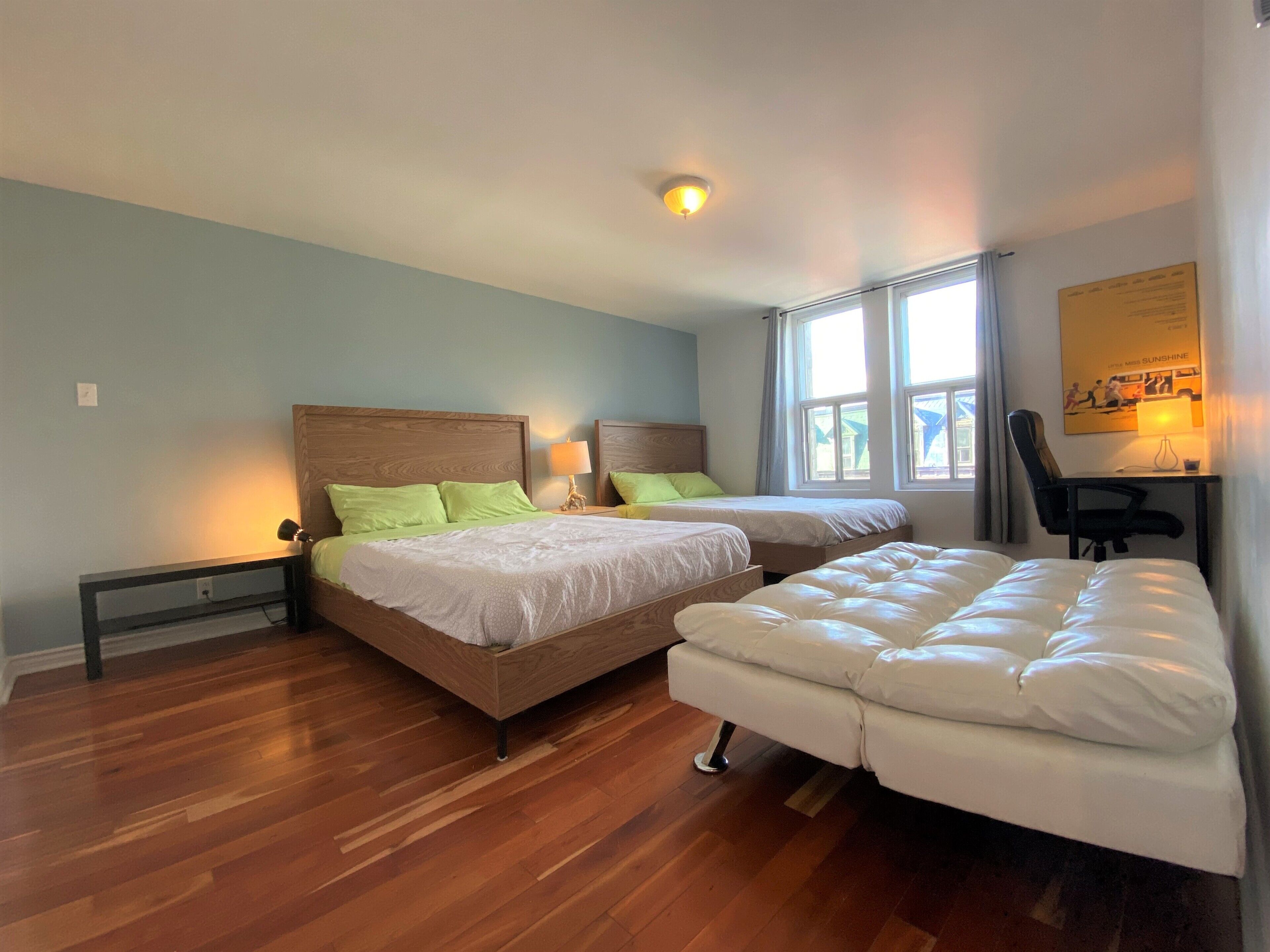 Quarto de hotel com duas camas, uma mesa e uma cadeira.