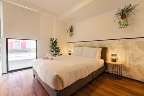 Une chambre moderne avec un grand lit, une plante en pot et une vue par la fenêtre.