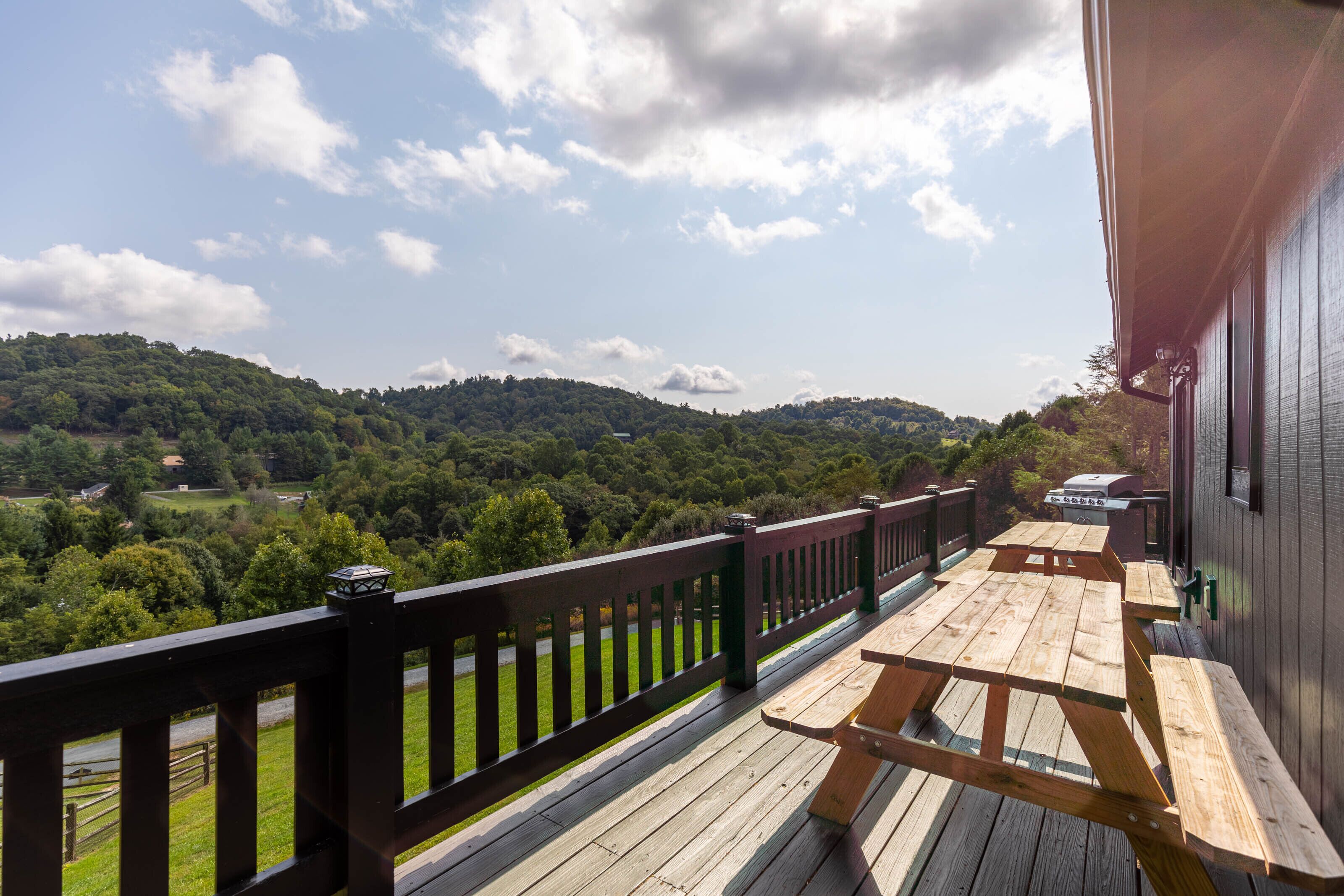 Eine Holzdielen-Terrasse mit Picknicktischen mit Blick auf ein bewaldetes Tal.