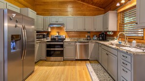 A modern kitchen with stainless steel appliances, white cabinets, and a wooden ceiling. - Horse Valley Lodge - Pool Table, Firepit, Indoor fireplace, Pet Friendly (Boone)