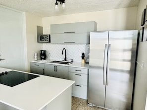 A modern kitchen with a stainless steel refrigerator, a microwave, and a coffee maker.