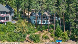 A multi-story house surrounded by dense forest, with a visible staircase leading to a deck. - Lake CDA: Soak, Paddle, Dock & Unwind (Coeur D Alene)