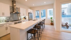 A modern kitchen with a large island, stainless steel appliances, and a view to the outside. - San Diego Beachfront House 60s to sand, surf, pier (Imperial Beach)