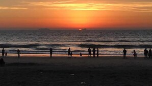 A beach scene with people walking along the shore during sunset. - San Diego Beachfront House 60s to sand, surf, pier (Imperial Beach)