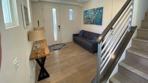 A modern living room with a sofa, a lamp, a painting, and a staircase. - San Diego Beachfront House 60s to sand, surf, pier (Imperial Beach)