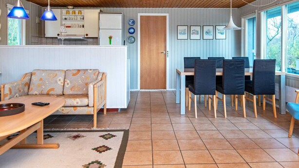 A cozy kitchen with a wooden ceiling, a dining area with a table and chairs, and a sofa. - 5 Person Holiday Home in Sydals (Sydals)