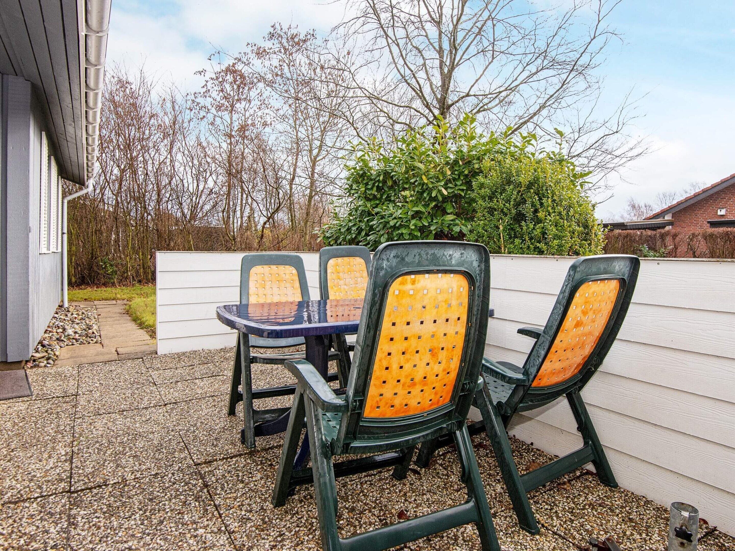 Eine Terrasss mit Tisch und vier Stühlen.