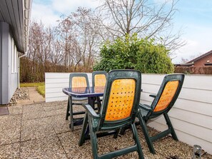 Um pátio externo com uma mesa e quatro cadeiras.