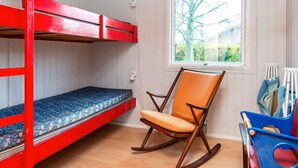 A bunk bed with a patterned mattress, a rocking chair, a window with a view of trees, and a blue toy storage unit. - 5 Person Holiday Home in Sydals (Sydals)