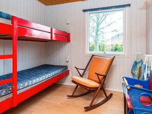 A bunk bed with a patterned mattress, a rocking chair, a window with a view of trees, and a blue toy storage unit. - 5 Person Holiday Home in Sydals (Sydals)