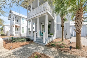 A two-story house with a porch, a balcony, and a palm tree.