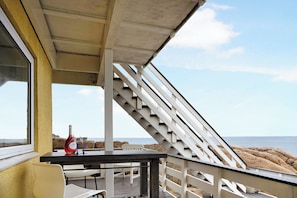 A deck with a table, chairs, and a bottle of wine.