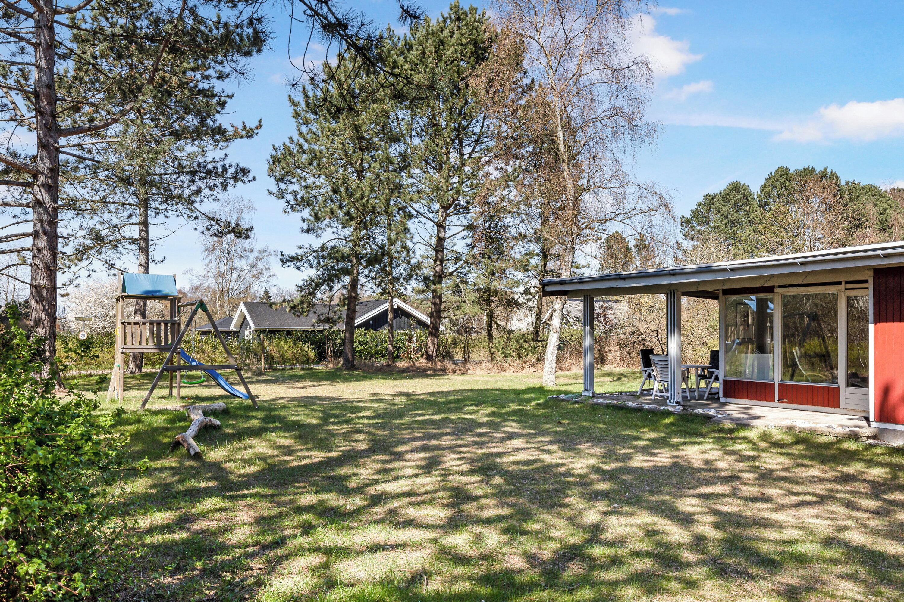 A backyard with a wooden play structure, a covered patio area, and a house.