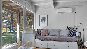 Una habitación con cama, ventana, un área de juegos al aire libre y un equipo de aire acondicionado.