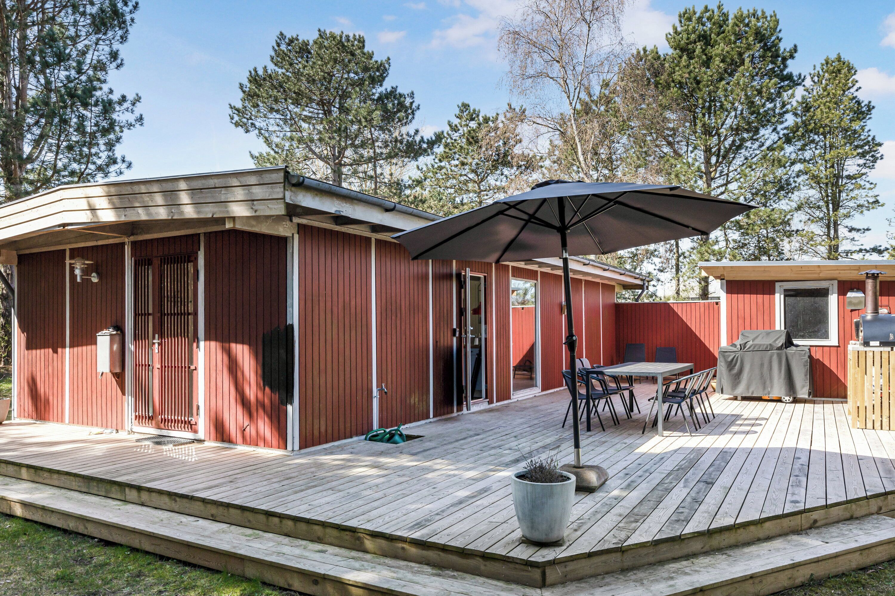 A wooden deck with a covered seating area, a grill, and a large umbrella.