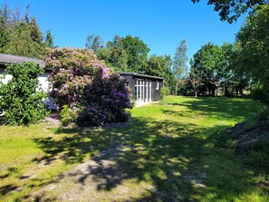 A house with a garden, a lawn, and trees in the background. - Lovely holiday home with spa and hot tub outside (Hals)