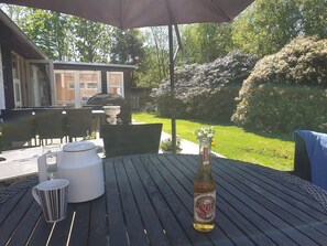 Une terrasse extérieure avec une table, des chaises, un barbecue et une bouteille de bière Sol.