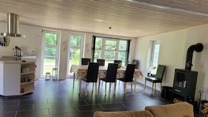Una sala de estar moderna con comedor, chimenea y ventanas amplias.