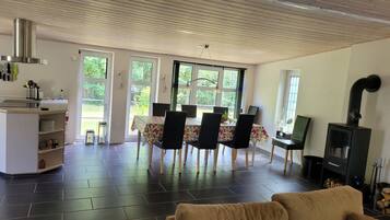 A modern living room with a dining area, a fireplace, and large windows.