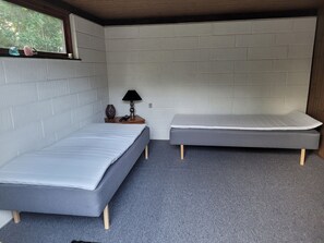 A small, compact room with two single beds, a nightstand with a lamp, and a window with a view of trees. - Lovely holiday home with spa and hot tub outside (Hals)