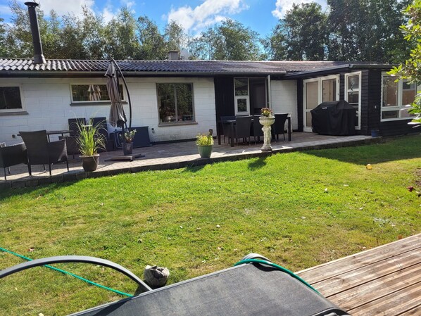 Une maison avec un patio, un espace salon extérieur et un jardin.