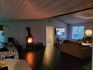 Una sala de estar acogedora con una estufa de leña, televisor, sofá y comedor con mesa y sillas.
