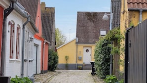 A cobblestone street with buildings on either side, a clear sky, and a small tree in the center. - Cozy holiday home in Marstal on Ærø (Marstal)