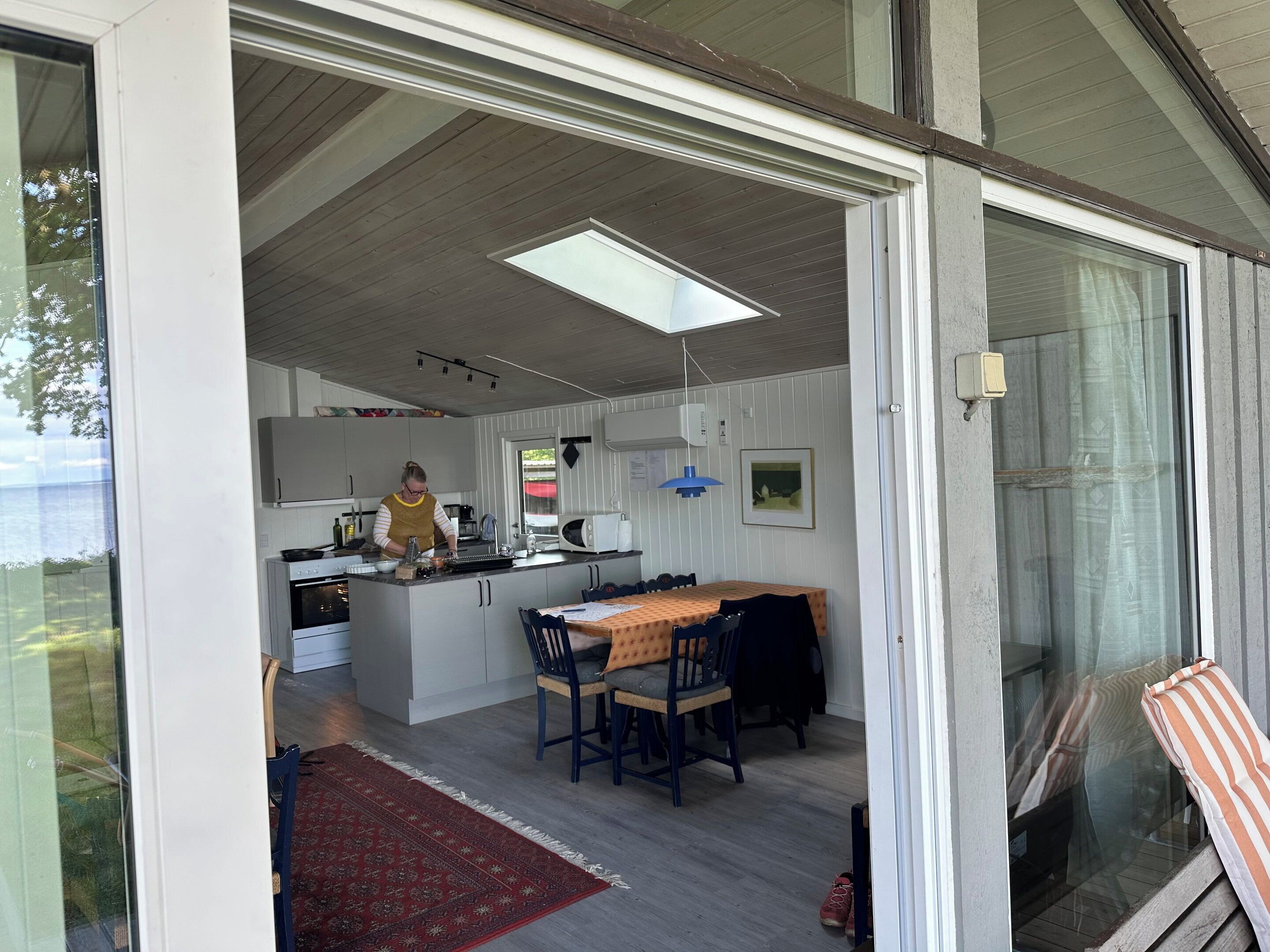 Una cocina moderna con una isla central, un comedor con mesa y sillas, y vistas al mar a través de amplios ventanales.