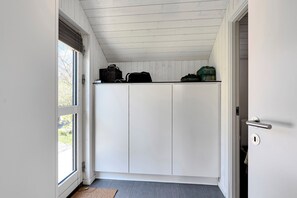 A room with a white door, a window, and a ceiling with wooden panels.