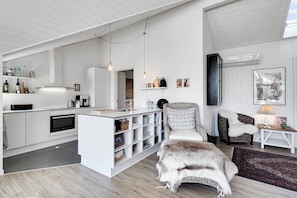Een moderne keuken met witte kastjes, een inbouw-kookeiland en hanglampen.