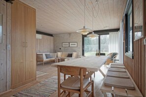 A modern interior with a wooden dining table, chairs, and a large window.