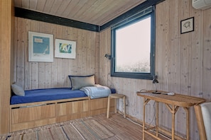 Une pièce dans une cabane en bois, avec un lit, une petite table et une fenêtre.