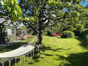 A hammock tied to a tree, a house with a patio, and a well-maintained lawn.