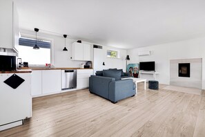 A modern kitchen with white cabinets, a grey sofa, and a flat-screen TV. - Amazing holiday home with view at the water (Vig)