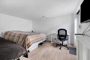 Et soveværelse med seng, skrivebord og stol.
