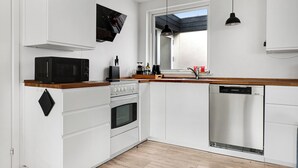 A modern kitchen with white cabinets, a microwave, stove, and dishwasher. - Amazing holiday home with view at the water (Vig)