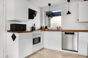A modern kitchen with white cabinets, a microwave, stove, and dishwasher. - Amazing holiday home with view at the water (Vig)