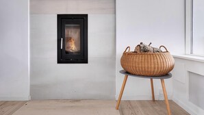 A modern room with a fireplace, a wicker basket on a table, and a window. - Amazing holiday home with view at the water (Vig)