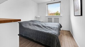 A bedroom with a bed, a window, a lamp, and a ceiling light. - Amazing holiday home with view at the water (Vig)