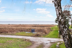A natural landscape with a path, a tree, and a body of water in the distance. - Amazing holiday home with view at the water (Vig)