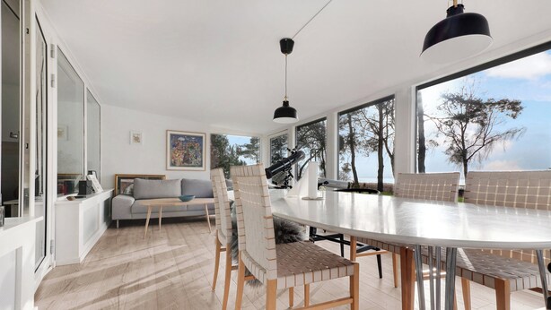 A modern interior with a dining area, sofa, and large windows offering a view. - Amazing holiday home with view at the water (Vig)