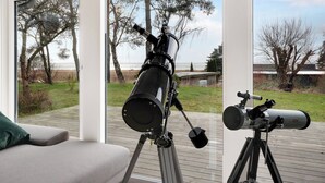 A telescope on a tripod on a deck with a view of trees and a grassy area. - Amazing holiday home with view at the water (Vig)