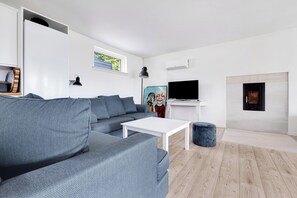 A modern living room with a gray sofa, white coffee table, and a fireplace. - Amazing holiday home with view at the water (Vig)